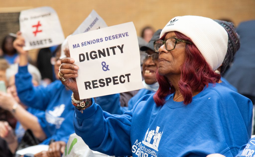 Member of MA Senior Action Council holds a sign "Dignity and Respect"